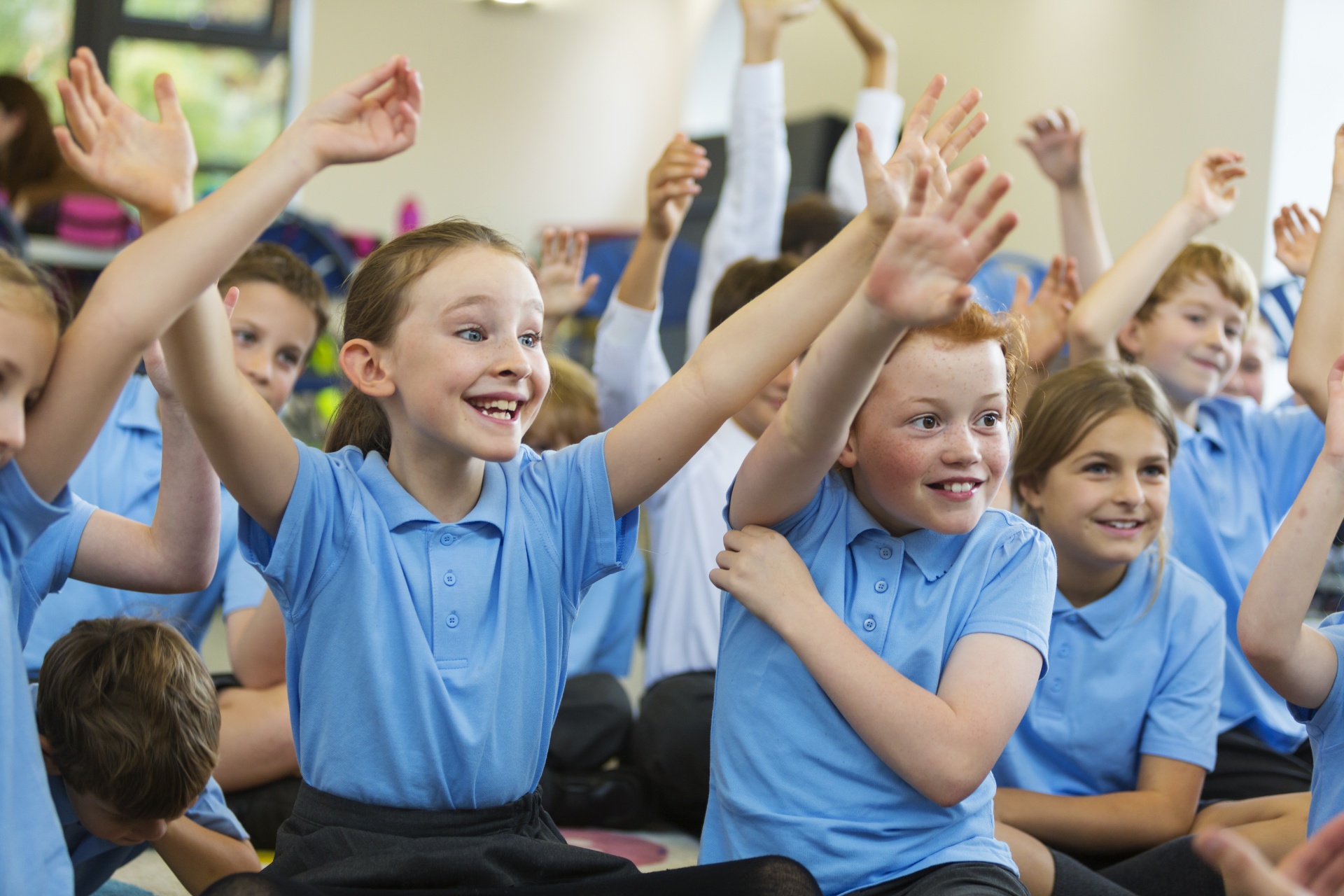 Group of children sitting smiling with their arms in the air